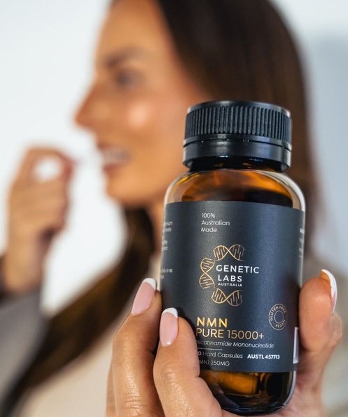 This creative showcases an NMN supplement bottle in sharp focus, held in the foreground, with a blurred consumer in the background taking a dose.